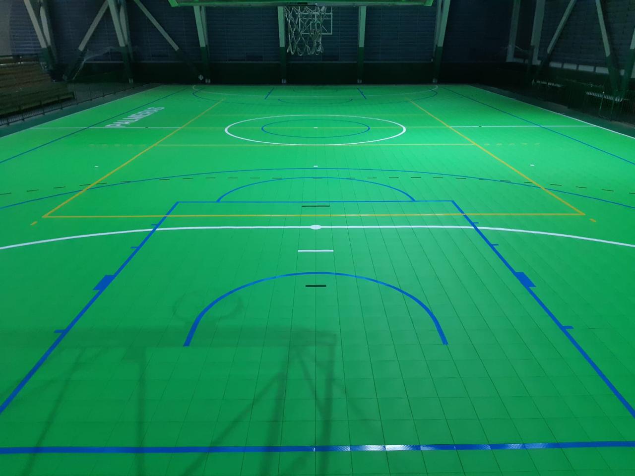Quadra poliesportiva verde com piso modular e demarcações